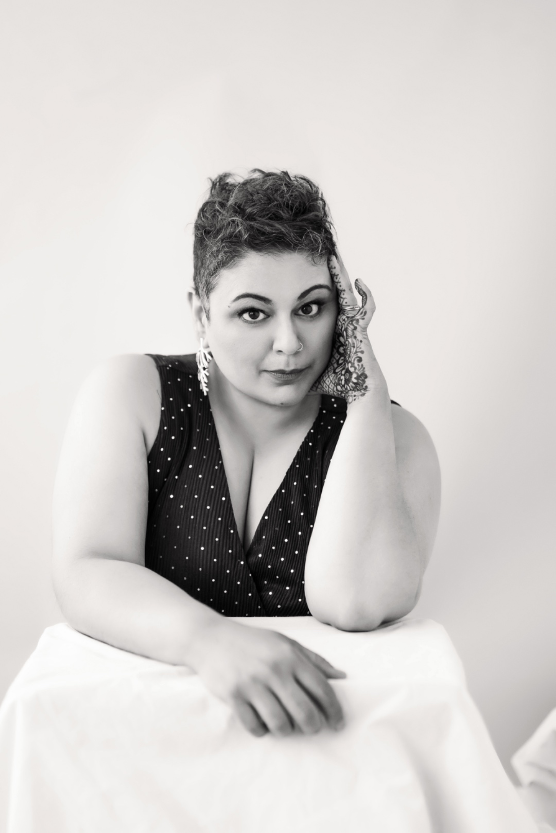 Farah Kidwai in a thoughtful black-and-white portrait, resting her head against her henna-adorned hand