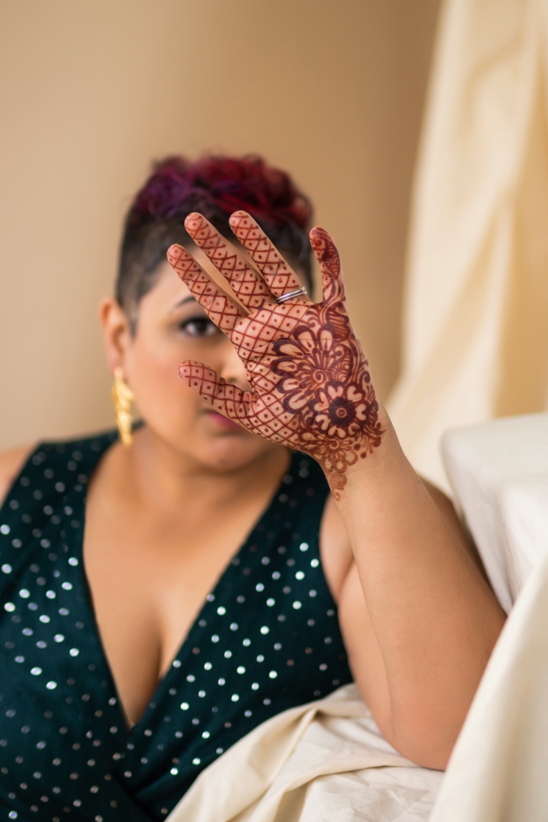 Farah displaying intricate henna artwork on her hand, partly covering her face
