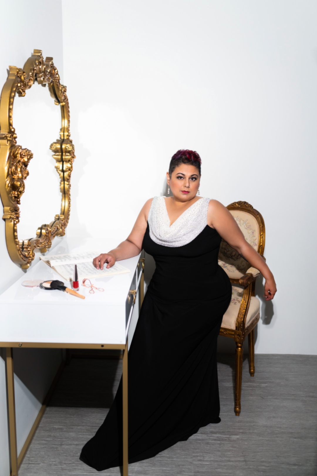 Farah in a black gown at an ornate gold vanity mirror